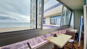 A room with a view of the beach, a window, a table, and a chair. - 2-Bedroom Apartment with Ocean View (Saint-Hilaire-de-Riez)