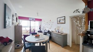 A compact living space with a dining area, kitchenette, and a small seating area. - 2-Bedroom Apartment with Ocean View (Saint-Hilaire-de-Riez)