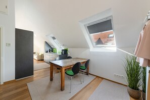 Een moderne keuken met een eethoek, dakraam en uitzicht op een gebouw met rode dakpannen.