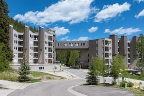 A multi-story residential building with balconies, a covered walkway, and a parking area. - Iron Horse Resort Unit C-1083 ski-in/out family condo rental (Winter Park)