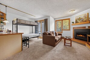 A compact living space with bunk beds, a sofa, a small table, and a fireplace. - Iron Horse Resort Unit C-1083 ski-in/out family condo rental (Winter Park)