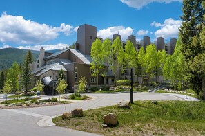 A modern building with a sloped roof, a covered entrance, and a landscaped driveway with trees and rocks. - Iron Horse Resort Unit C-1083 ski-in/out family condo rental (Winter Park)