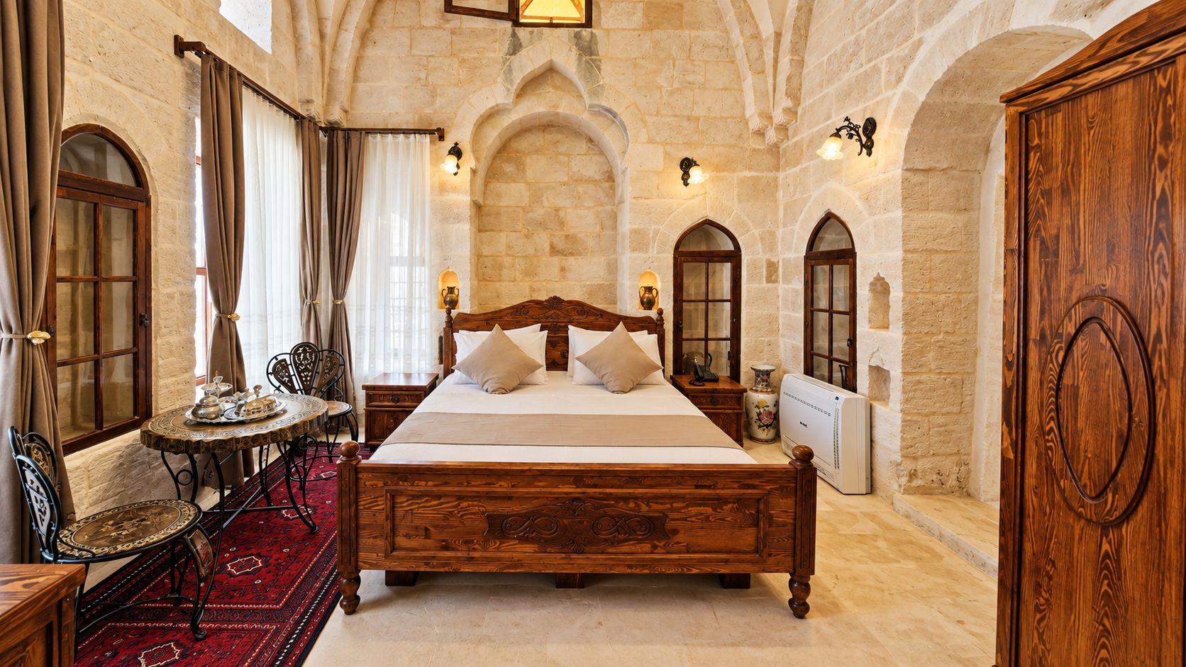Una habitación tradicional con una cama grande, un armario de madera y una pared de piedra.