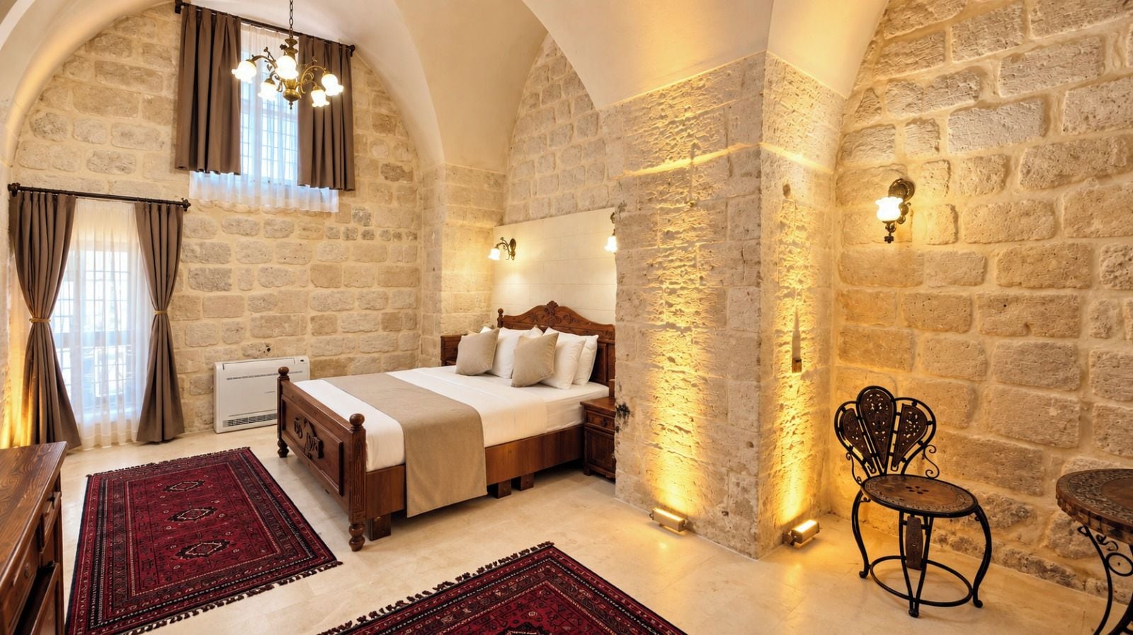 Un dormitorio con pared de piedra, cama de madera, alfombra roja y una silla de metal.
