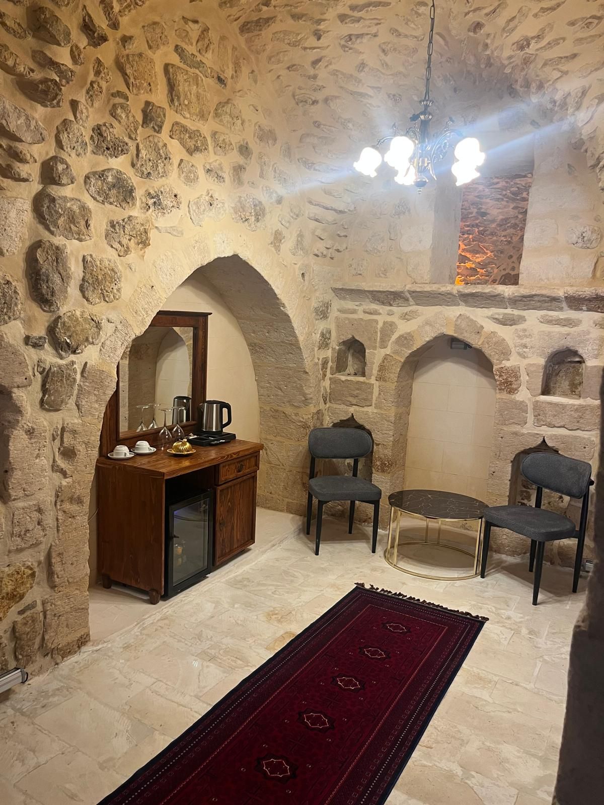 Une pièce aux murs de pierre, dotée d’une cheminée, d’un coin café et de deux fauteuils.
