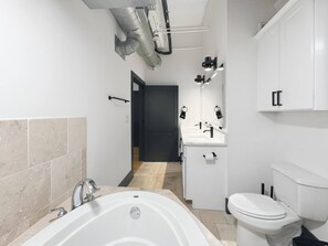A modern bathroom with a bathtub, toilet, and vanity. - 2-bedroom apartment in welcoming Downtown San Antonio (San Antonio)