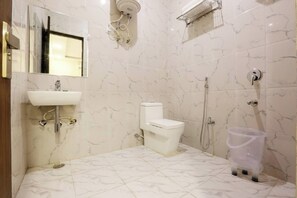Une salle de bain avec des toilettes blanches, un lavabo et un espace douche.