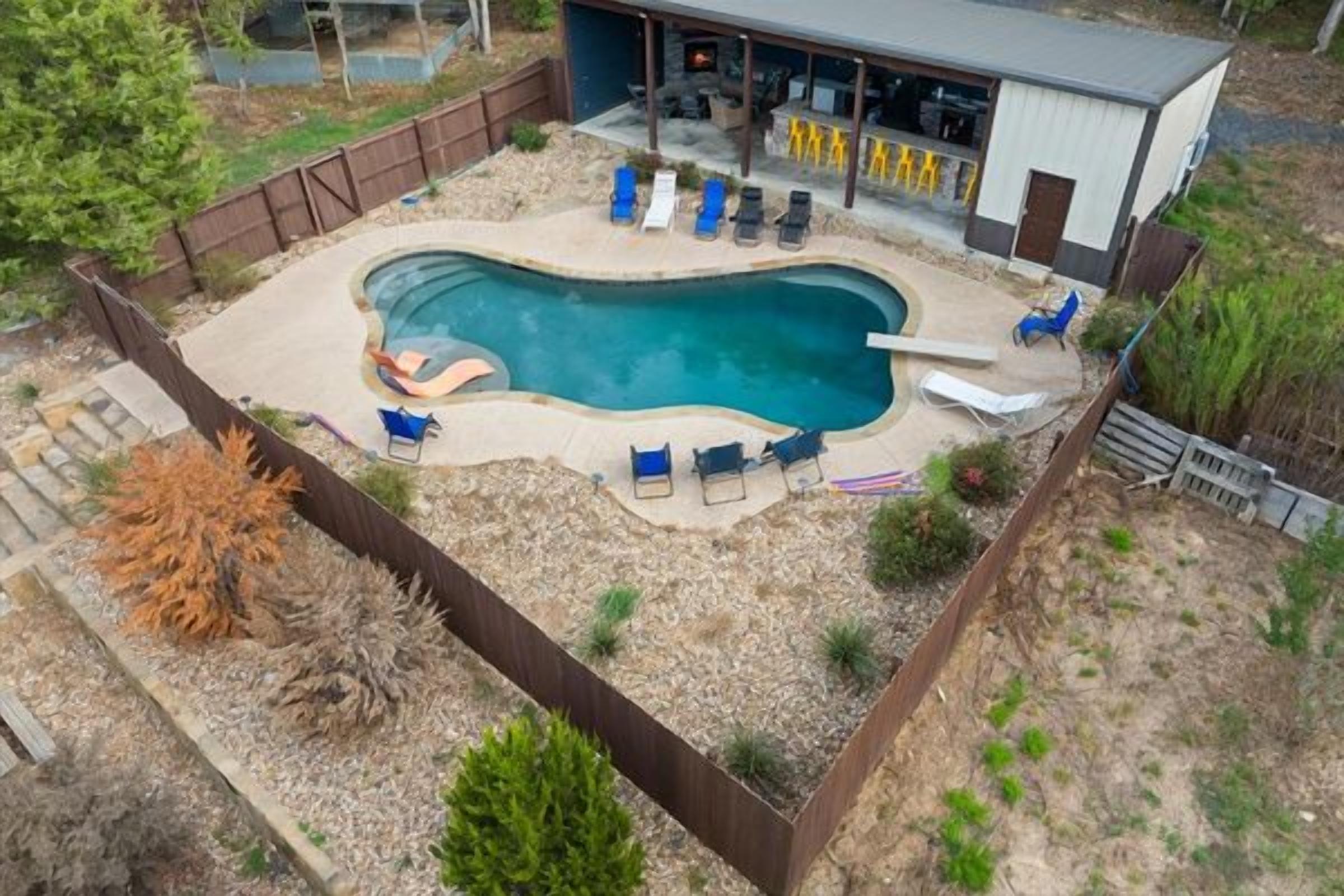 A swimming pool with lounge chairs, a covered patio, and a building with a bar area.