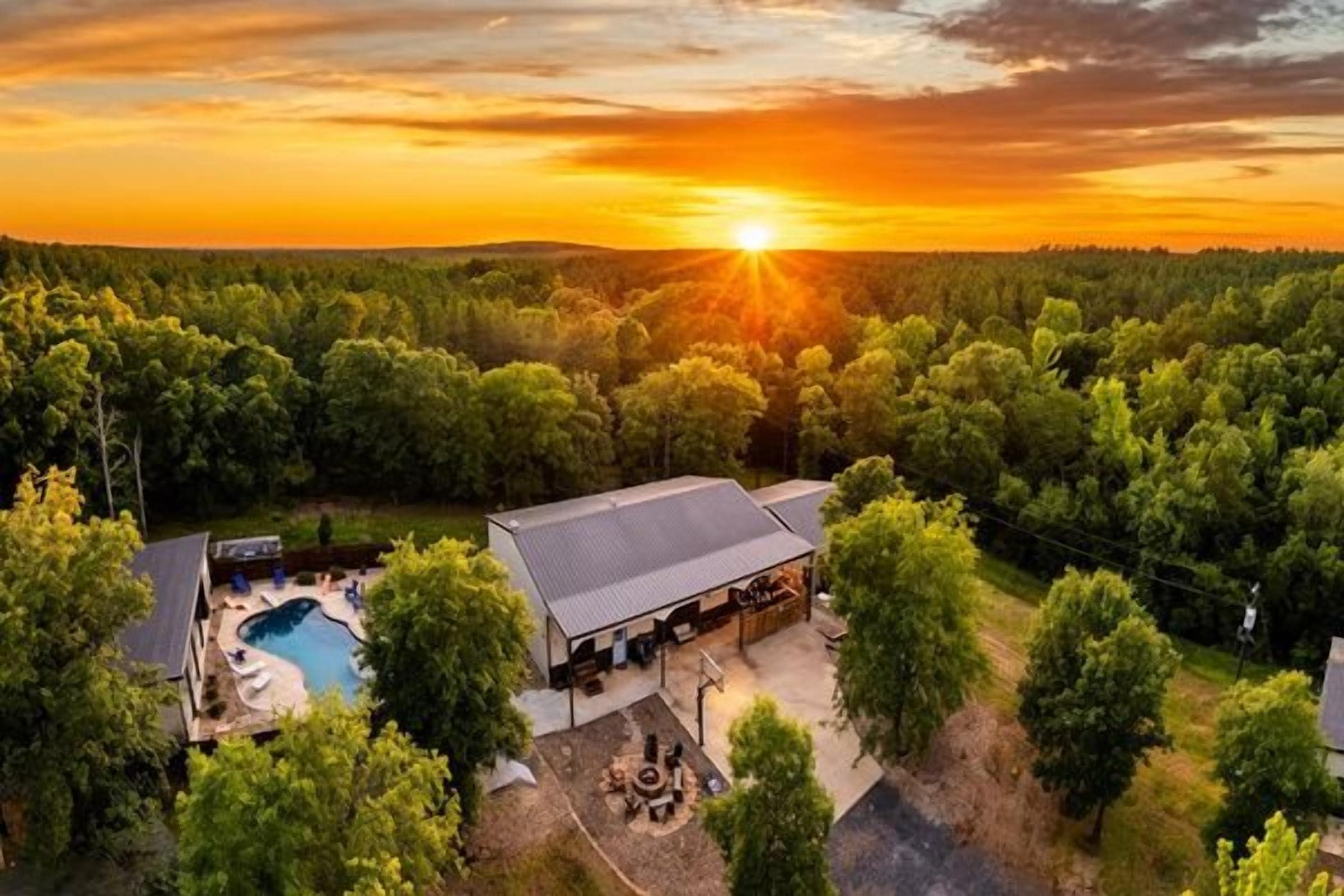 A property with a swimming pool, outdoor seating, and a large building with a flat roof.