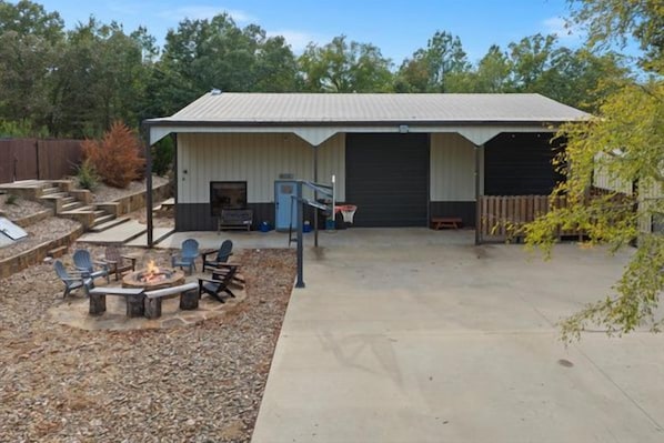 A building with a covered patio area, outdoor seating, and a fire pit. - Heated Pool | 14-Acre Ranch | Lake & Hot Tub (Broken Bow)