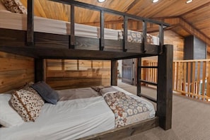 A bunk bed with a wooden headboard and a lower bed with patterned bedding. - Heated Pool | 14-Acre Ranch | Lake & Hot Tub (Broken Bow)