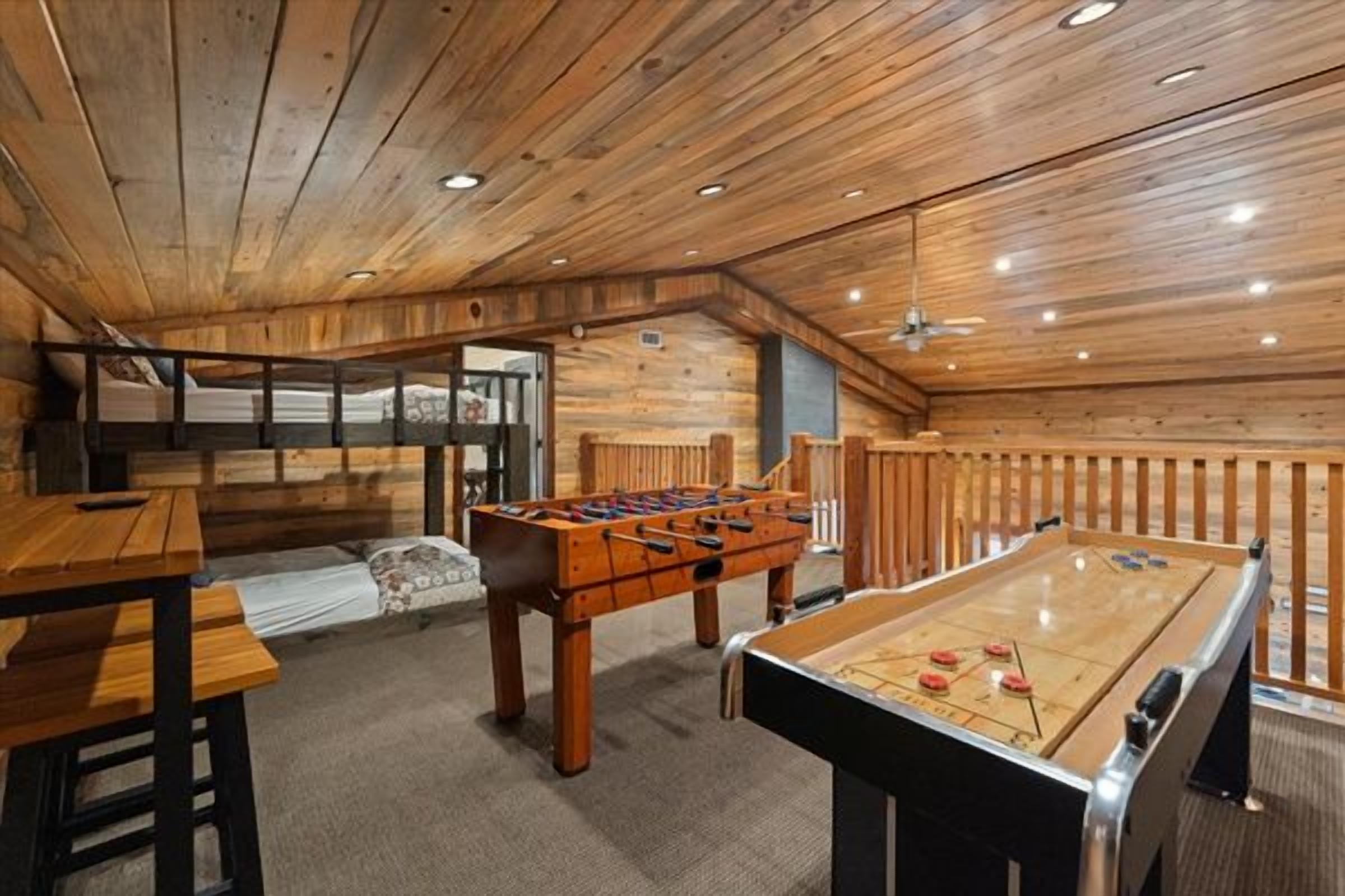 An indoor recreational area with wooden flooring, a foosball table, and a pool table.