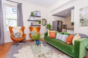 A modern living room with a green sofa, two leather armchairs, a coffee table, and a patterned rug. - Essential Boston Home, Near South End (Boston)