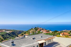A coastal town with terraced houses, a clear blue sky, and the sea in the background. - Blue House, a Home in Madeira (Ponta do Sol)