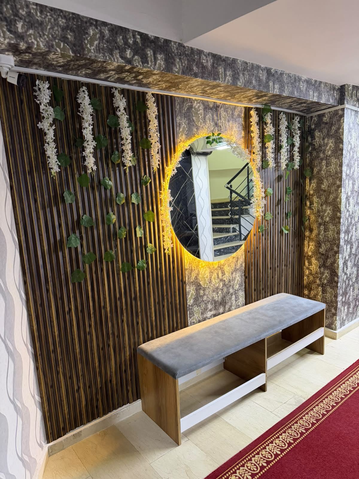 Un intérieur moderne agrémenté d’un banc, d’un miroir rond et de plantes décoratives.