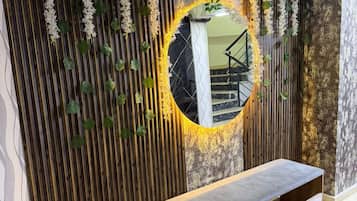 Un intérieur moderne agrémenté d’un banc, d’un miroir rond et de plantes décoratives.