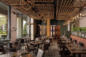 Ein Restaurant mit Ziegelwänden, Holztischen, Ledersitzbänken und einer Decke mit Kordelmuster.