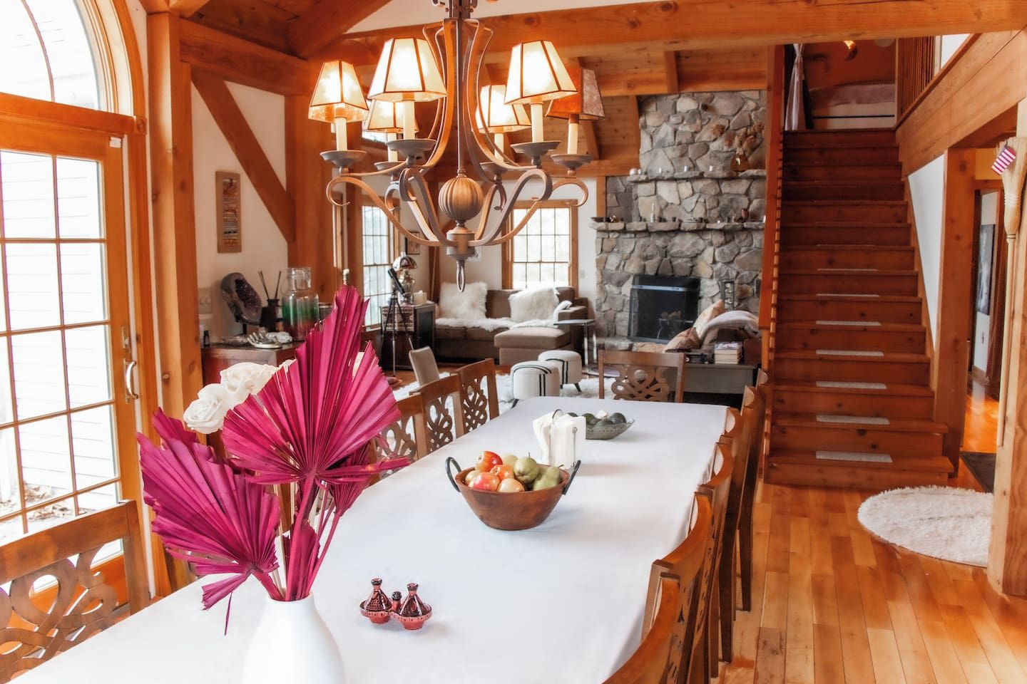 A spacious room with a long dining table, a chandelier, and a stone fireplace.