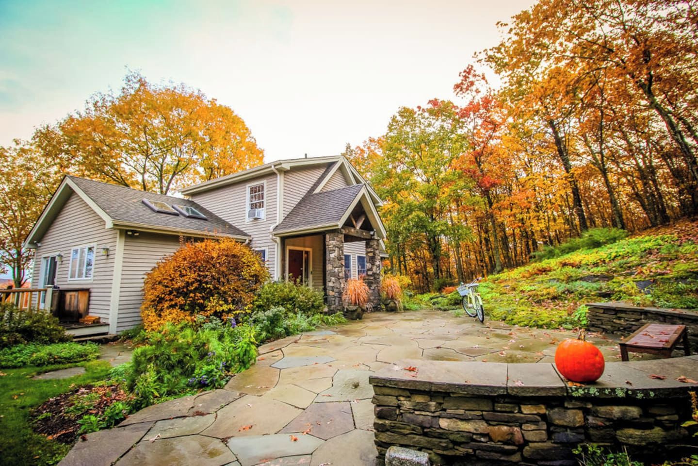 A two-story house with a stone foundation and a stone walkway leading to the entrance.