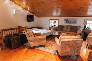A cozy room with a bed, two sofas, a coffee table, and a TV mounted on the wall. - Sacred Dream Entire Property-Hot Tub Copake Lake (Craryville)
