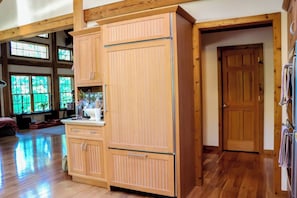 A spacious room with wooden flooring, a large cabinet with drawers, a door, and a window with a view of greenery. - Sacred Dream Entire Property-Hot Tub Copake Lake (Craryville)