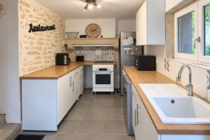 A kitchen with white cabinets, a wooden countertop, a built-in oven, a sink, and a clock on the wall. - La Maison Talvanne – Character home with private pool (Donzy)
