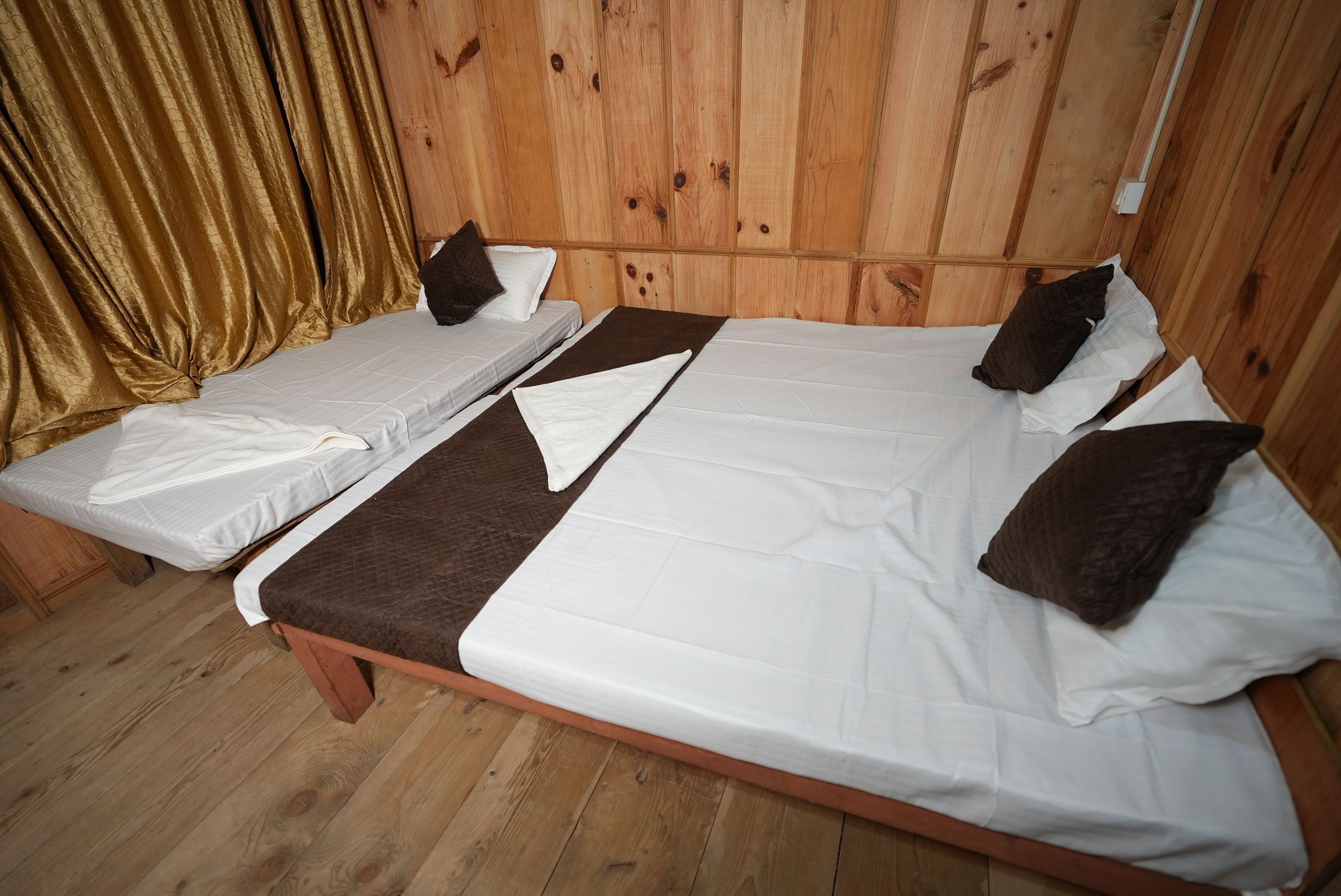 A room with two single beds, wooden flooring, and a wooden headboard.