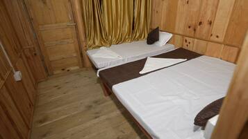 A room with two beds, wooden walls, and a curtain.