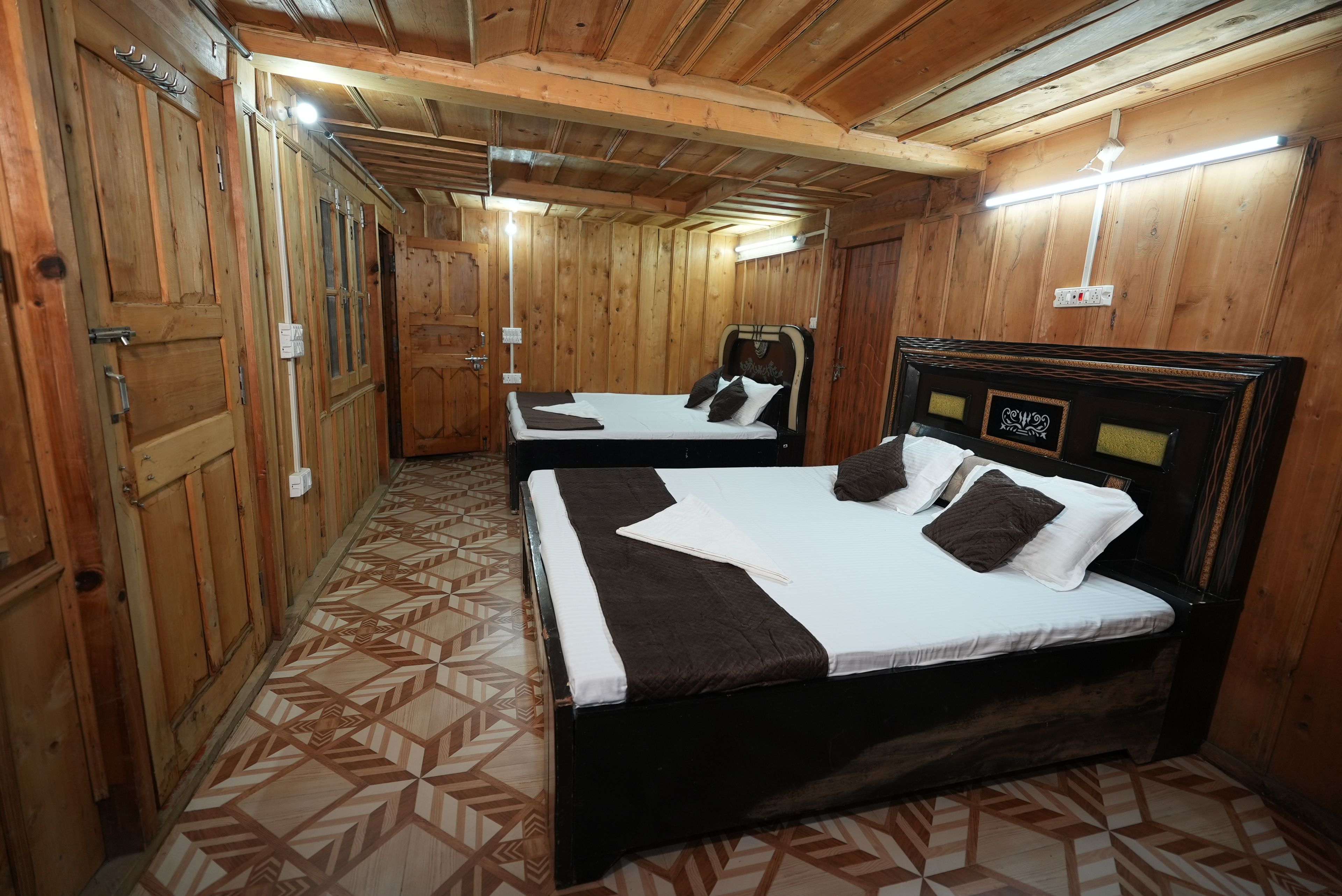 A wooden-paneled room with two beds, each with a headboard and pillows.