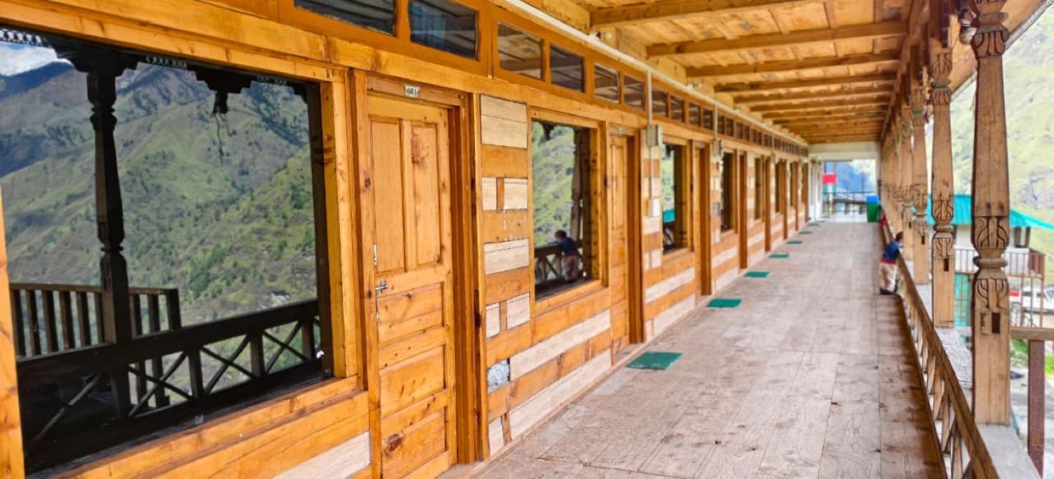 A wooden corridor with windows, a wooden floor, and a view of a mountainous landscape.