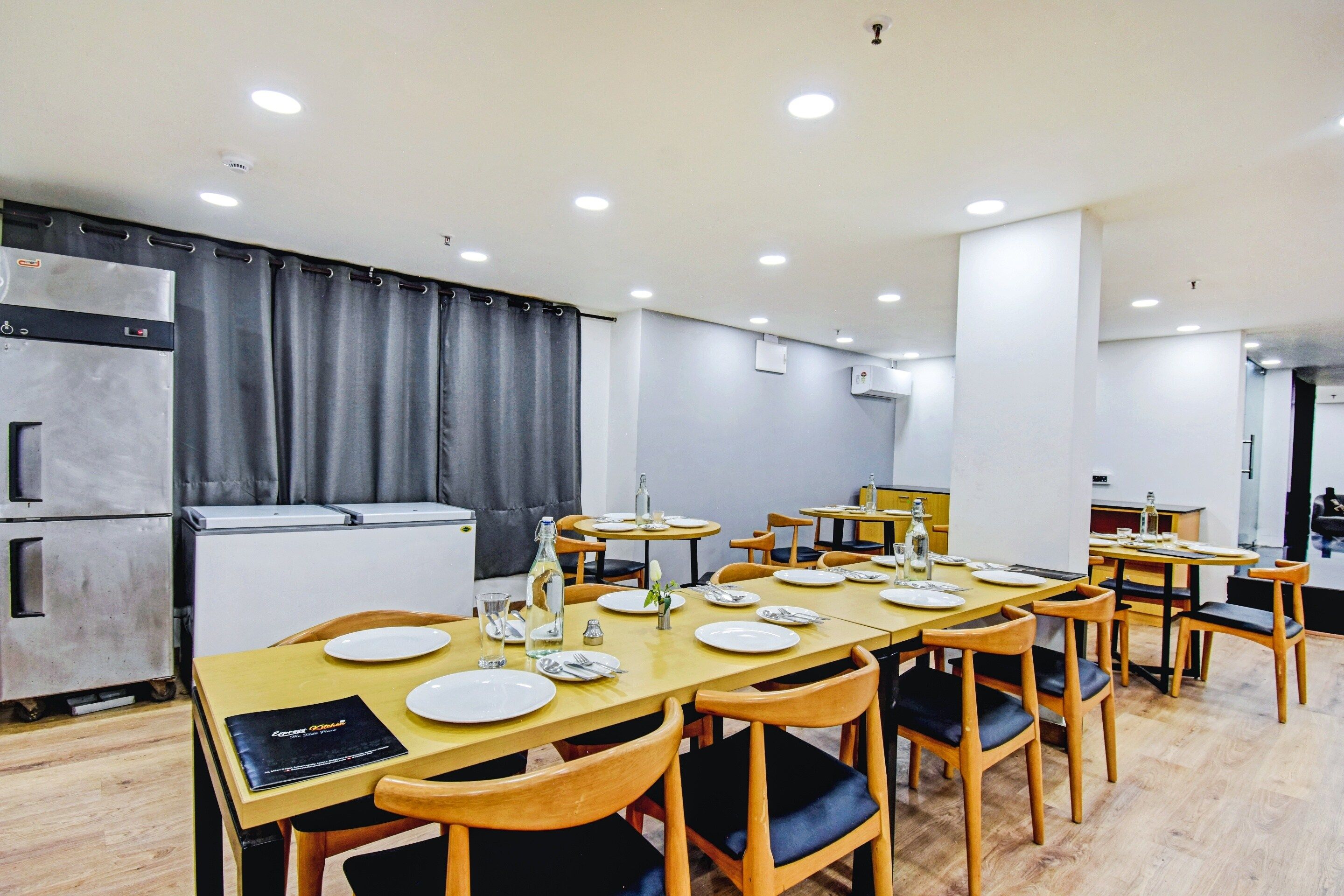 A dining area with tables set for four, equipped with plates, cutlery, and glasses.