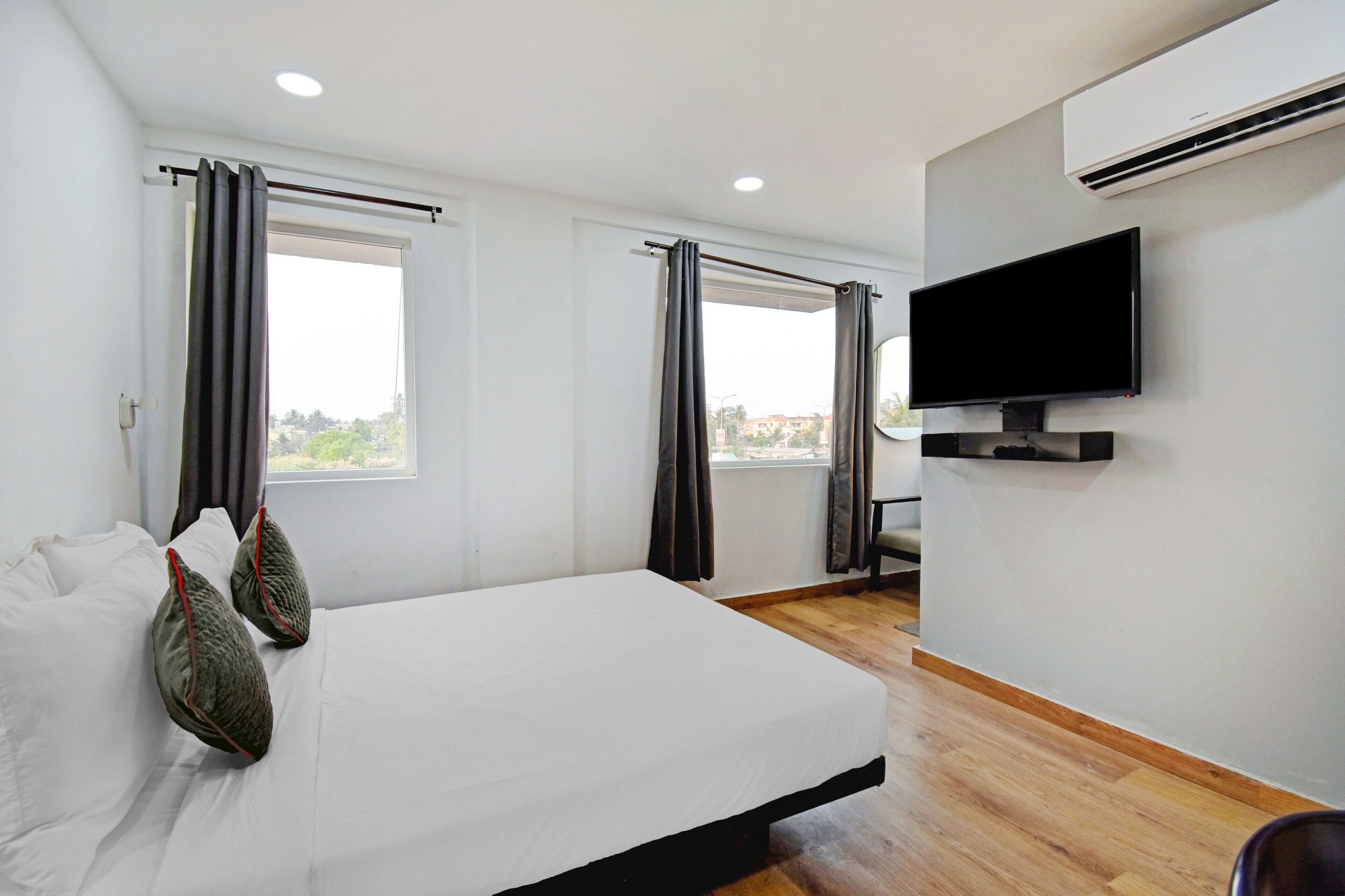 Una habitación de hotel con cama, televisión de pantalla plana y ventana con cortinas.
