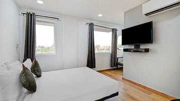 Una habitación de hotel con cama, televisión de pantalla plana y ventana con cortinas.