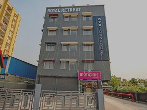A multi-story building with 'ROYAL RETREAT' and 'OYOTOWNHOUSE' signage, a closed shop named 'monginis' with a cake shop sign, and a gated entrance.