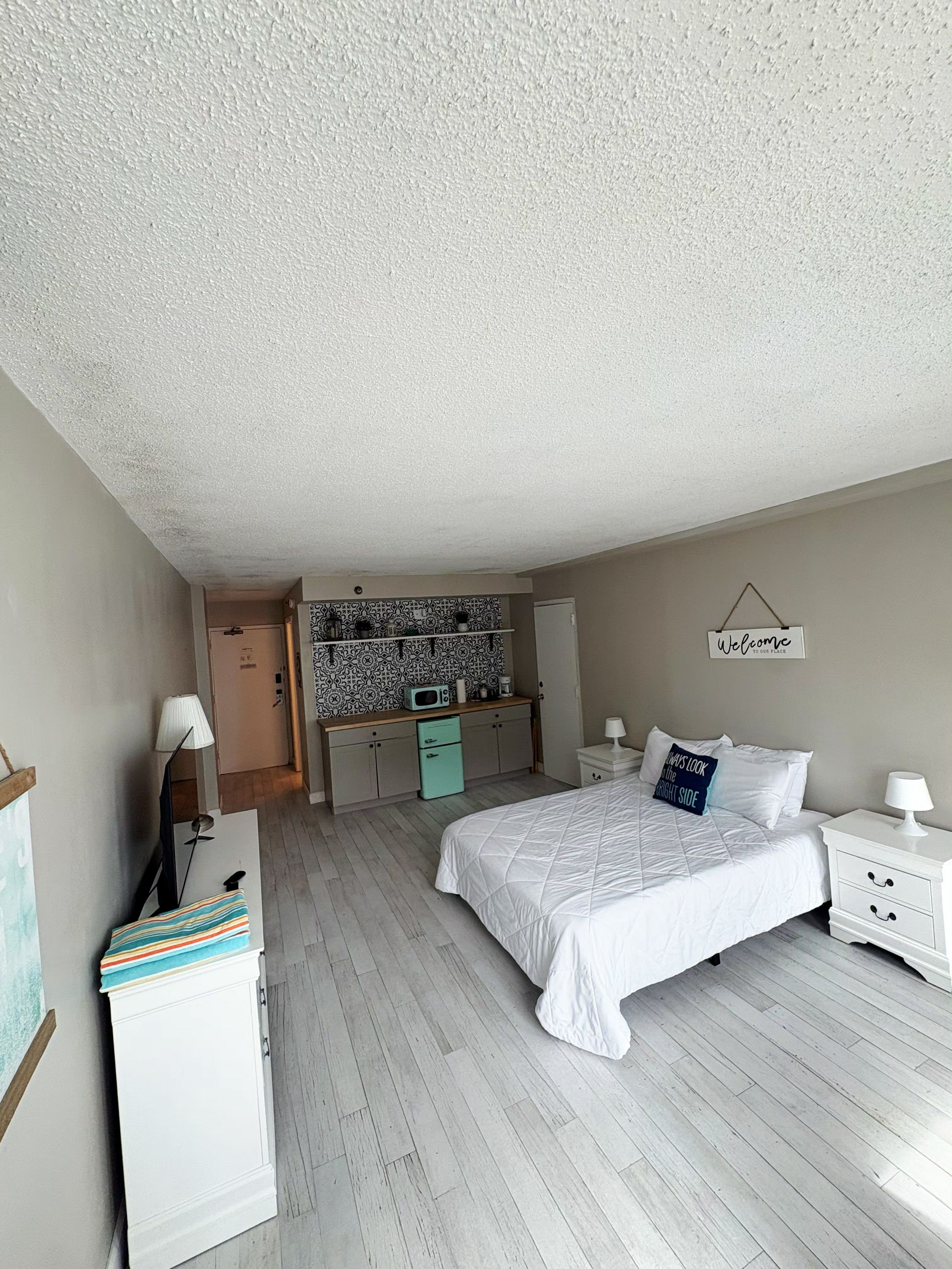 Une chambre à coucher comprenant un lit, des tables de chevet, un bureau avec une chaise, un four à micro-ondes et une armoire.