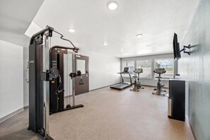 A gym with a weight machine, treadmill, and exercise bike.
