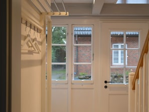 Eine weiße Tür mit Fenster, einem Metallgeländer und einer dahinter liegenden Ziegelwand.