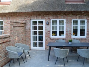 A brick exterior with a thatched roof, a white-framed window, and a table with chairs. - 5 Martinique at the Boldix House (Wyk auf Foehr)