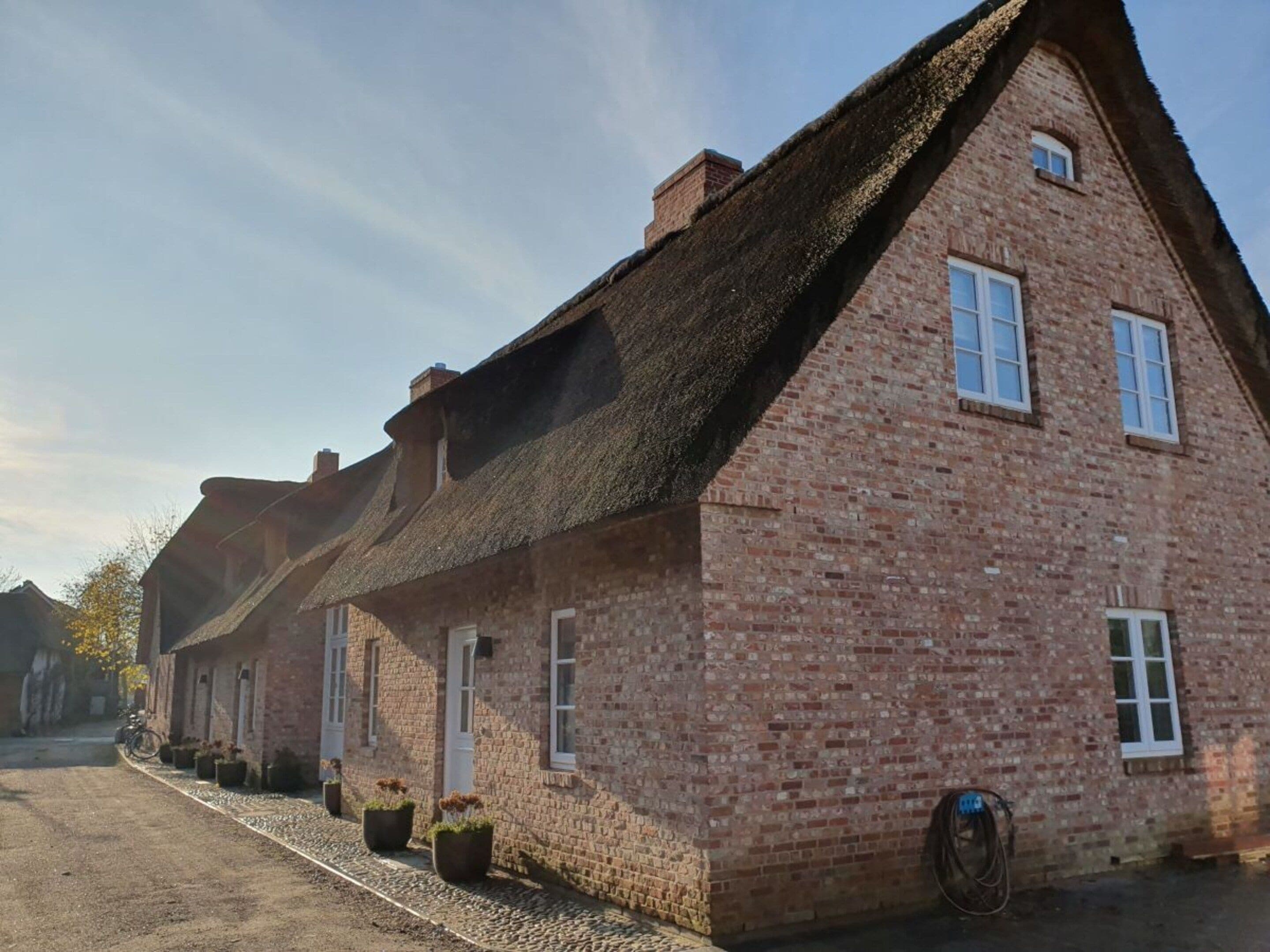 Una hilera de casas tradicionales de ladrillo con techos de paja y marcos de ventanas blancos.