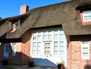 A traditional brick house with a thatched roof and a white garage door. - 5 Martinique at the Boldix House (Wyk auf Foehr)
