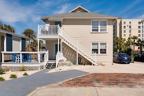 A two-story building with a balcony, a staircase, and a parking area. - High Tide · Upstairs 2BR · One Block to the Ocean (Jacksonville Beach)