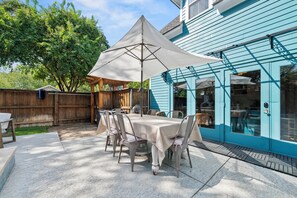 Une terrasse extérieure avec une table et des chaises, un parasol et une clôture en bois.