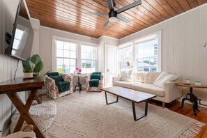 A room with a wooden ceiling, a sofa, two armchairs, a coffee table, and a TV. - Low Tide · 2BR/2BA · Private Deck · Steps to Sand (Jacksonville Beach)