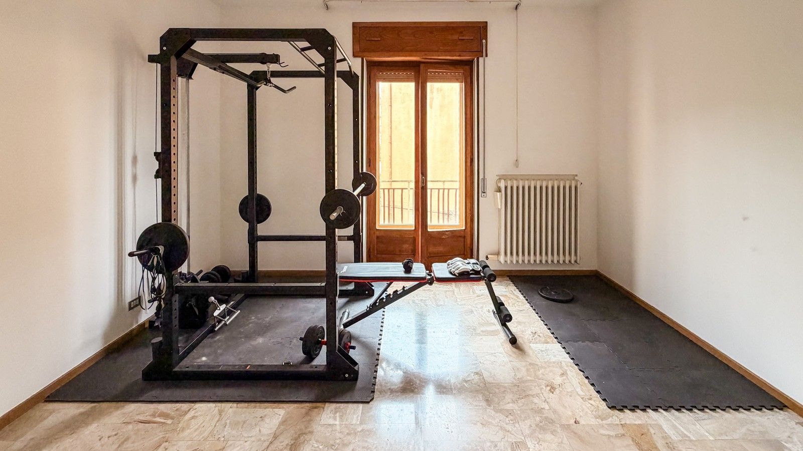 Une salle de sport équipée d’un support à squats, d’une barre et de disques de poids.