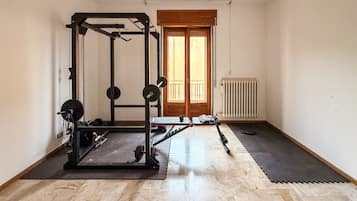 Une salle de sport équipée d’un support à squats, d’une barre et de disques de poids.