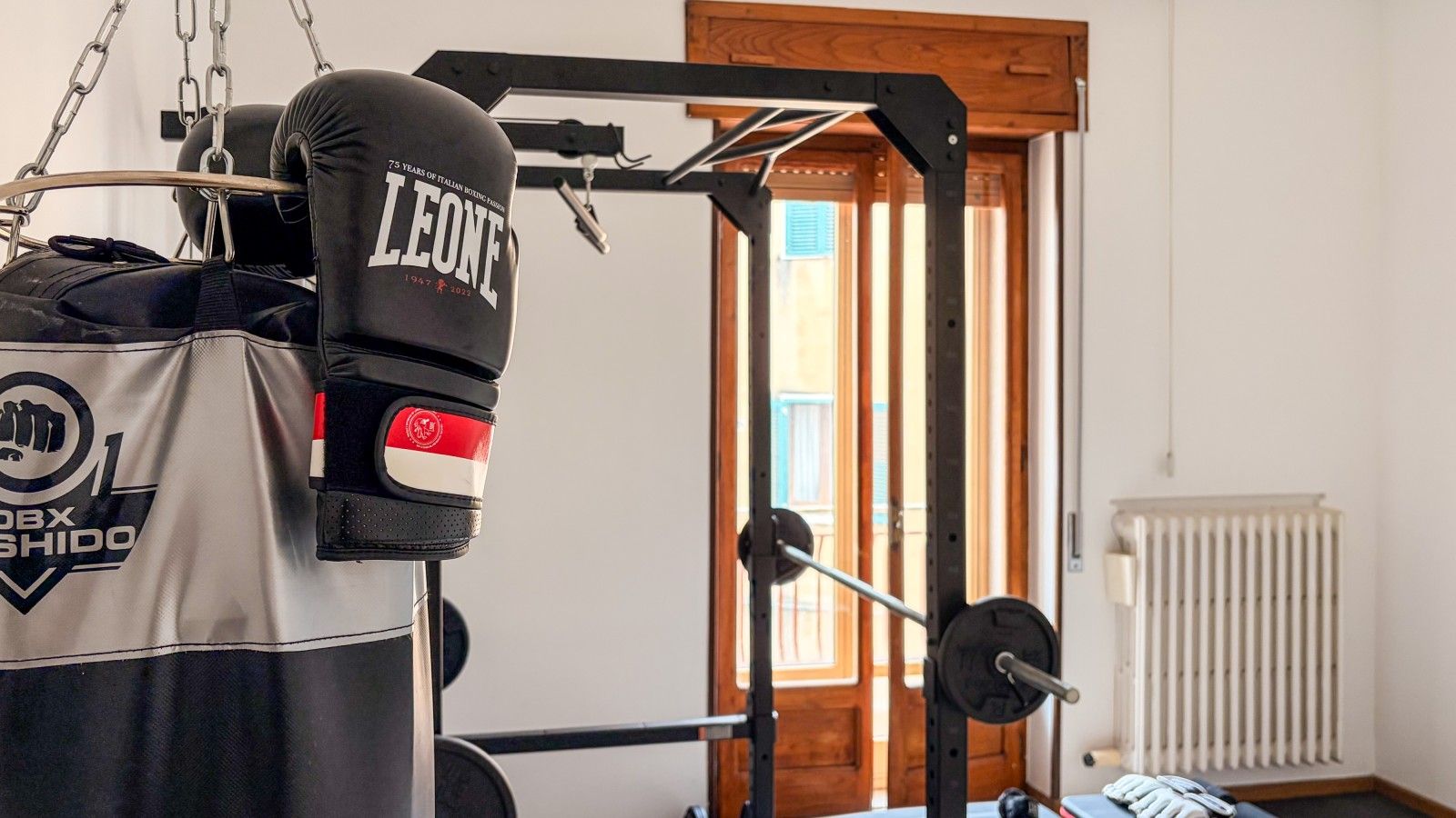 Une salle de sport équipée d’un sac de frappe, d’un banc de musculation et d’une porte donnant sur une autre pièce.