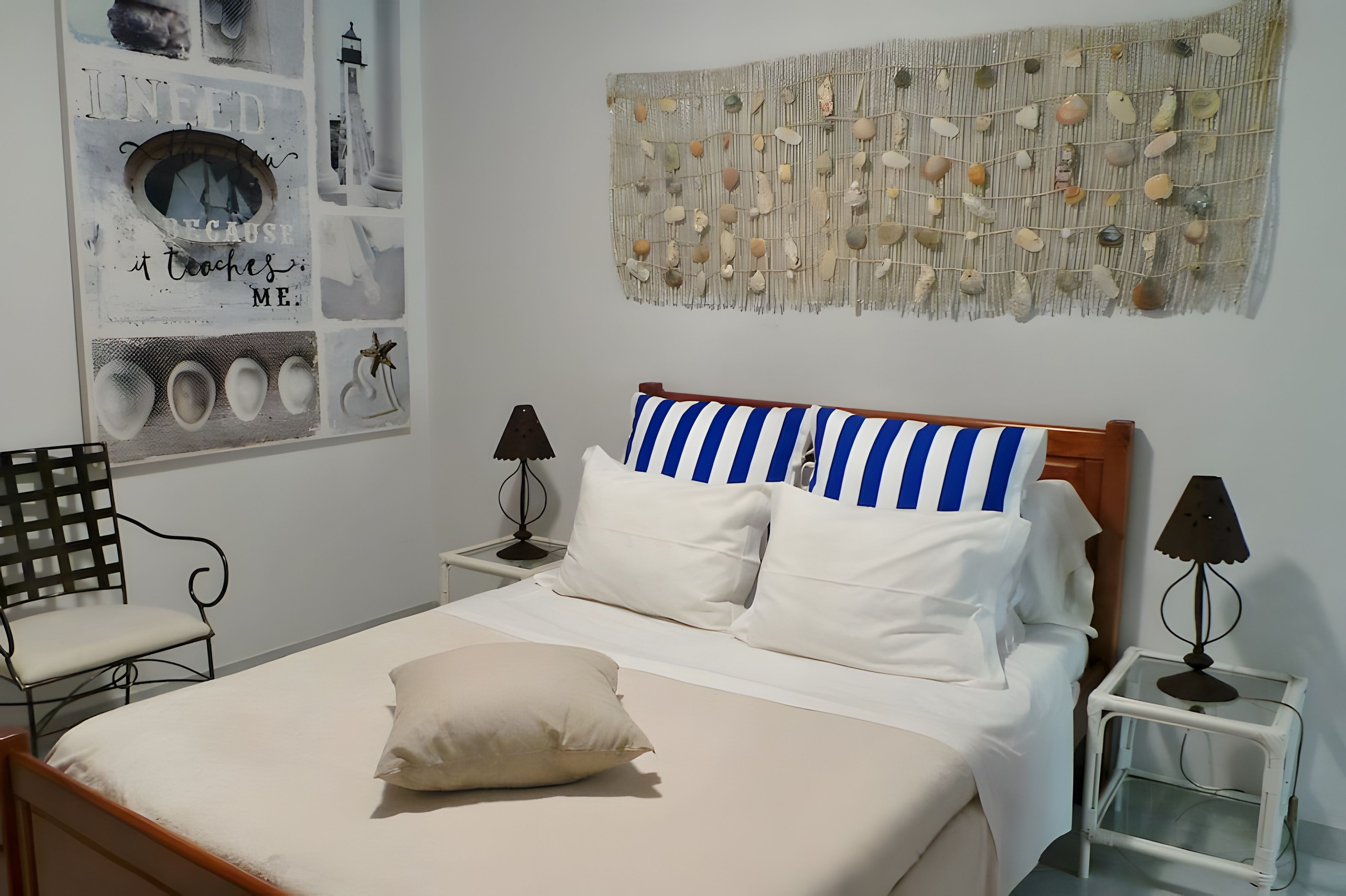 Una camera da letto con un letto, una sedia, un comodino, una lampada e un elemento decorativo a parete.