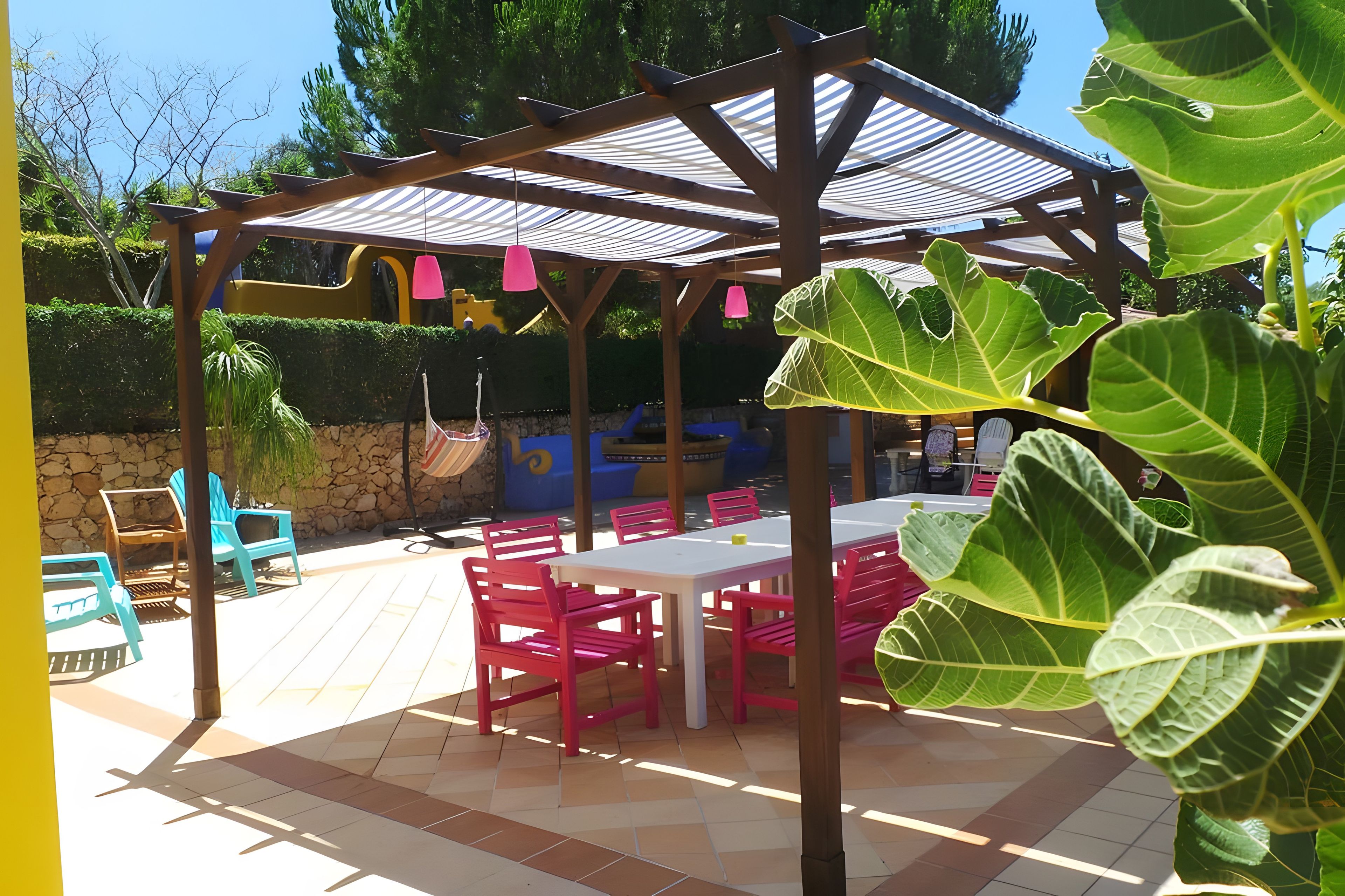 Un'area patio all'aperto con una pergola, posti a sedere e un tavolo.