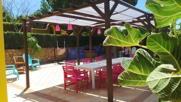 Un'area patio all'aperto con una pergola, posti a sedere e un tavolo.
