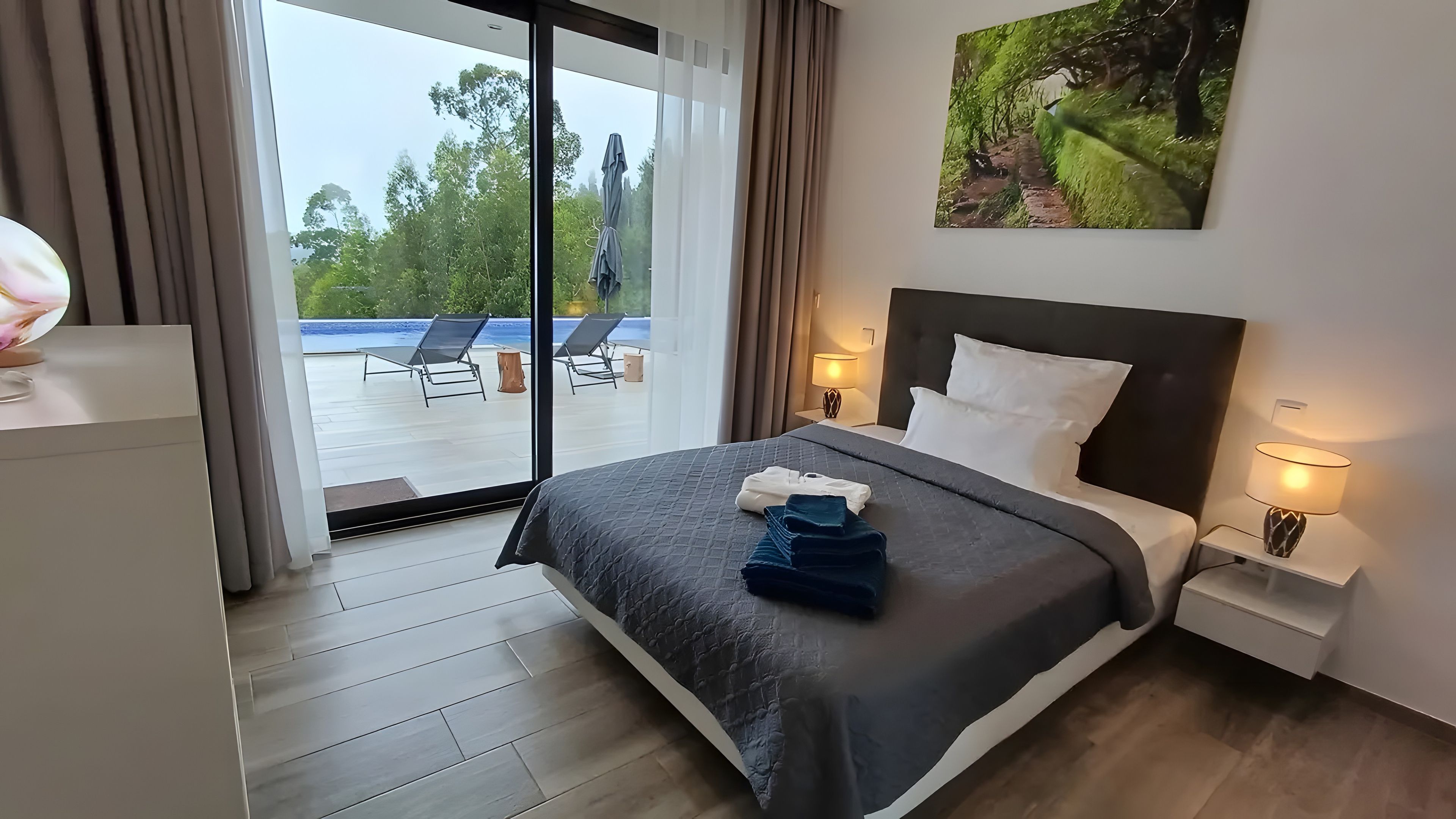 Une chambre d’hôtel comprenant un lit, un bureau, une chaise, une table de chevet, une lampe et une vue sur l’extérieur.